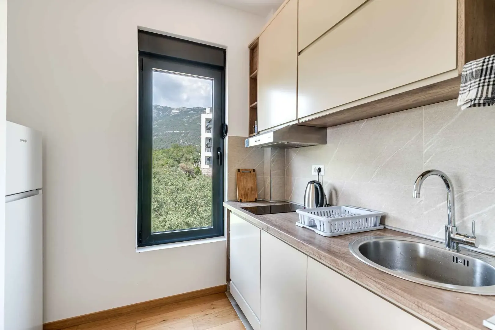 Modern kitchen with a sink, countertop, and a window with a view of nature.