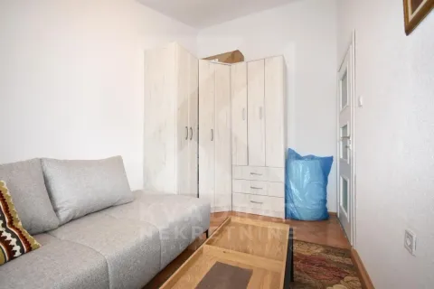 Dnevna soba sa sivom sofom, drvenim ormarima i stolićem. - image 9