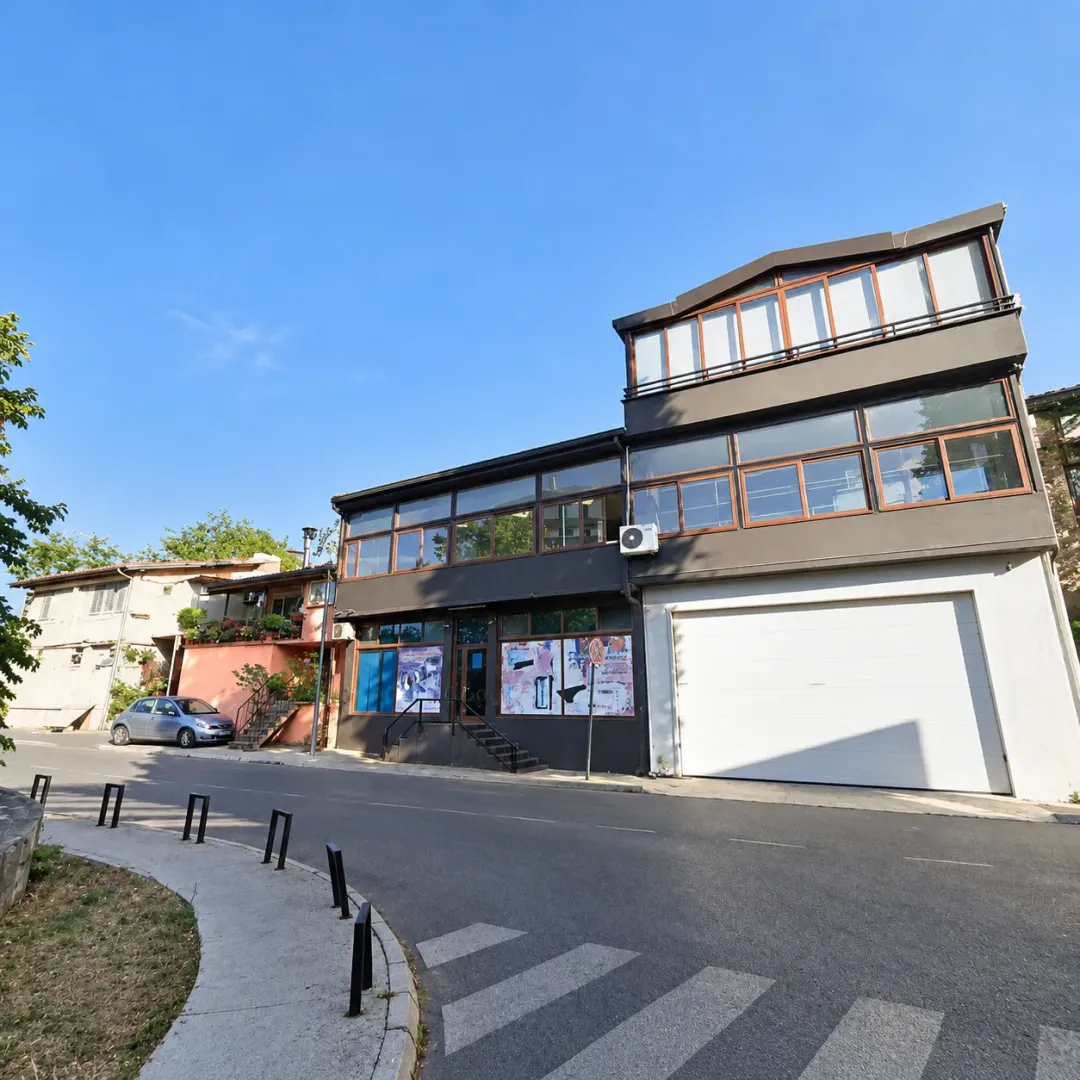 Exterior view of a three-story commercial and residential building with large display windows and a garage door.