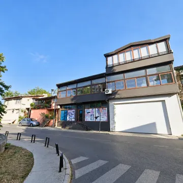 Exterior view of a three-story commercial and residential building with large display windows and a garage door. - image 10
