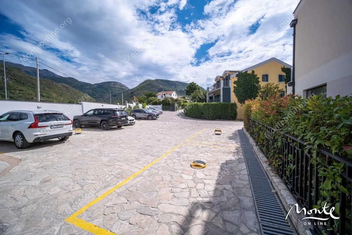 Parking prostor sa označenim mjestima ispred zgrade.