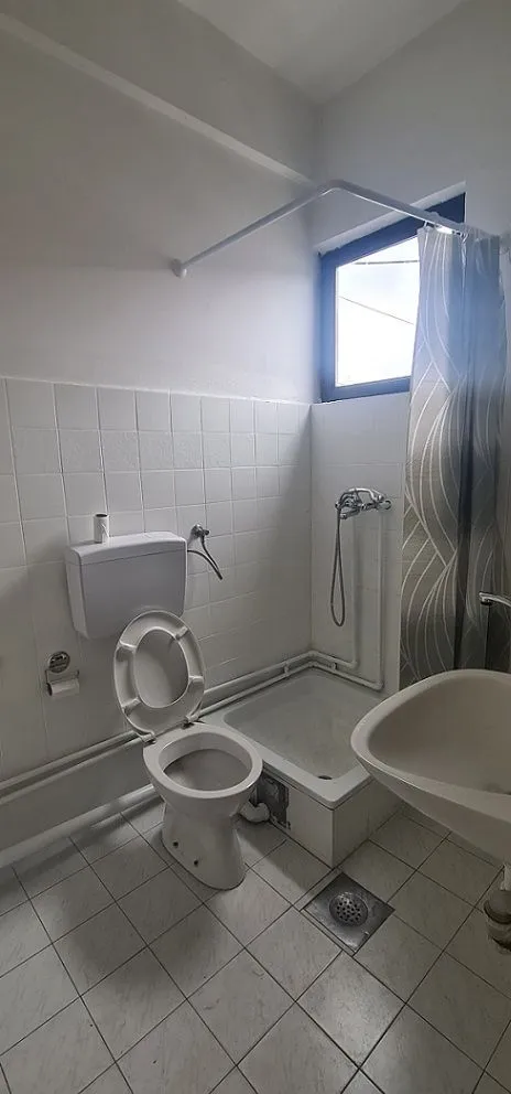Smaller bathroom with a shower cabin, toilet, and sink.