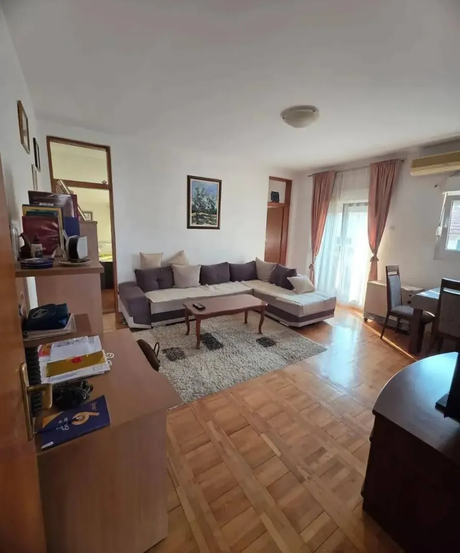 Dnevna soba sa garniturom, drvenim podom i trpezarijskim dijelom.