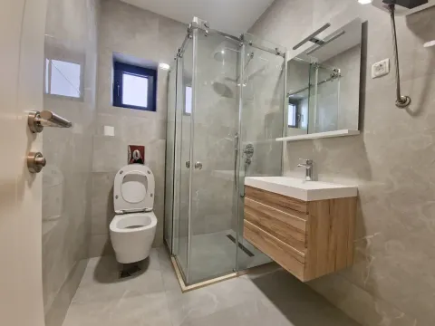 Modern bathroom equipped with a shower cabin, washbasin, and toilet. - image 9
