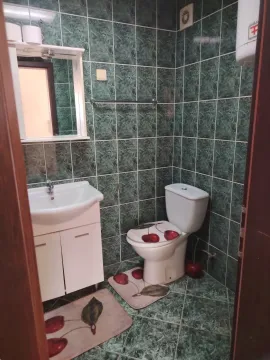 Manje kupatilo obloženo zelenim pločicama sa umivaonikom i wc šoljom. - image 10