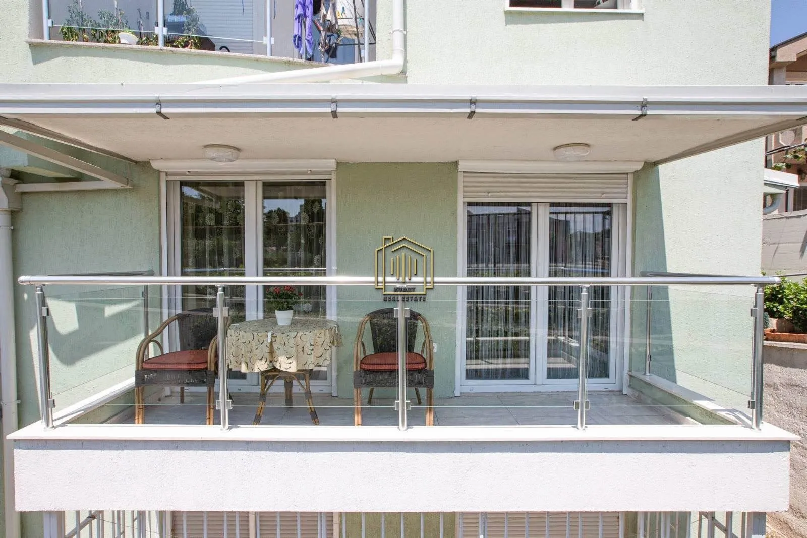 Covered balcony with a glass railing and outdoor seating furniture.