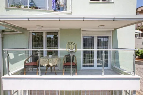 Covered balcony with a glass railing and outdoor seating furniture. - image 10