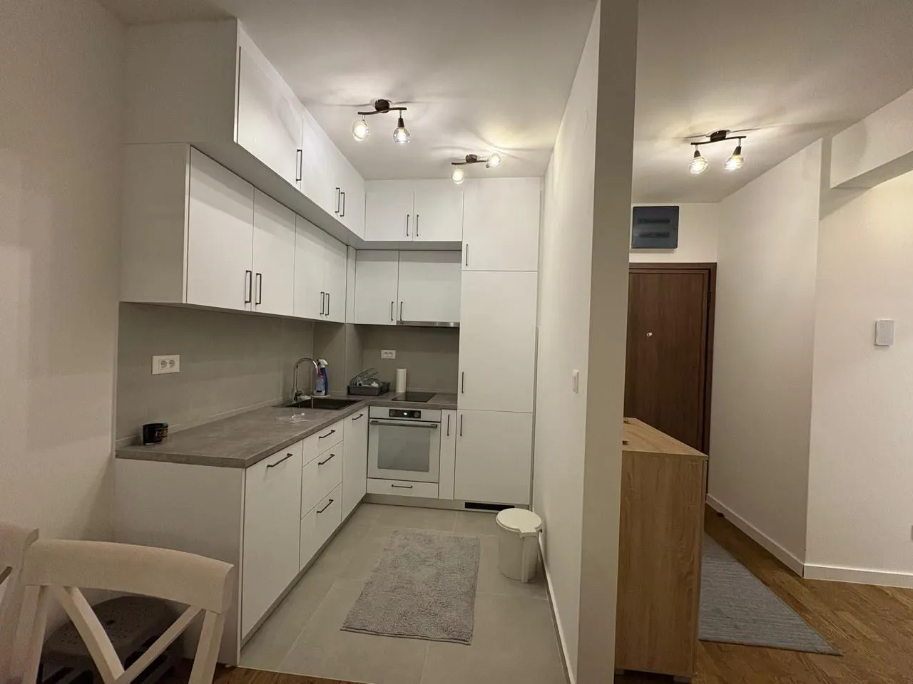 Modern white kitchen with built-in appliances and a dining table.