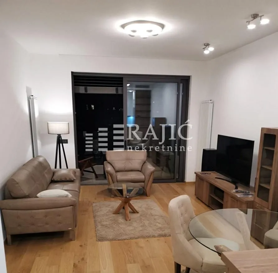 Furnished living room with a sofa, TV, and dining table.