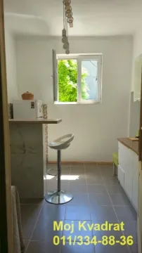 Manja kuhinja sa šankom, barskom stolicom i prozorom sa pogledom na zelenilo. - image 6