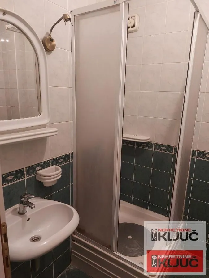 Manje kupatilo sa tuš kabinom i umivaonikom.