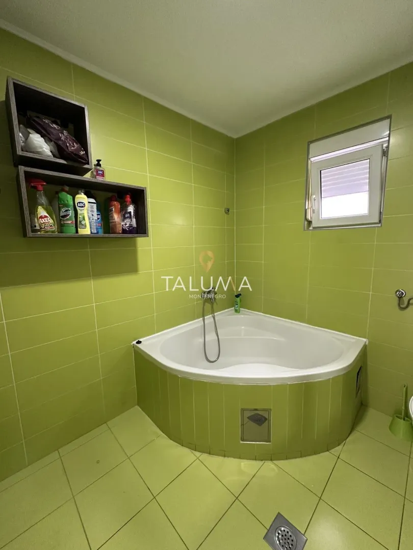Bathroom with a corner bathtub and green tiles.