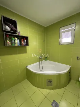 Bathroom with a corner bathtub and green tiles. - image 14