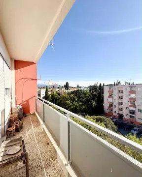 Dugi natkriveni balkon sa pogledom na okolne zgrade i zelenilo. - image 6