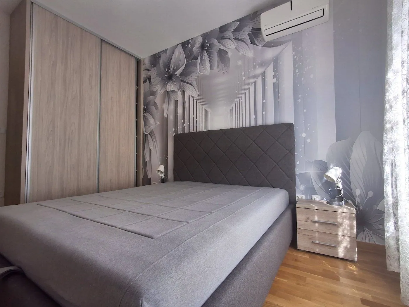 Modern bedroom with a double bed, built-in wardrobe, and decorative wallpaper.