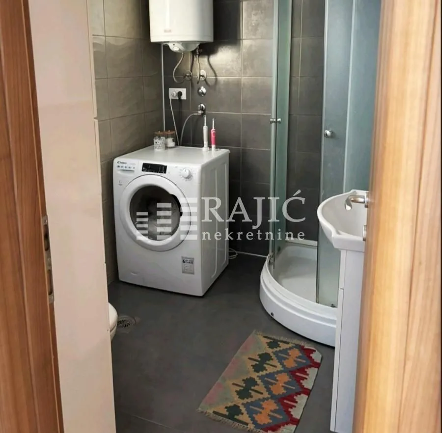 Small bathroom with a shower cabin and washing machine.