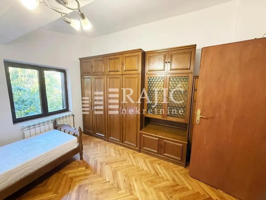 Furnished bedroom with wooden wardrobe and bed.