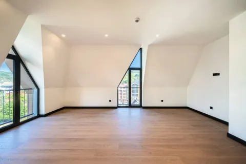 Spacious empty room with wooden flooring and large windows. - image 8