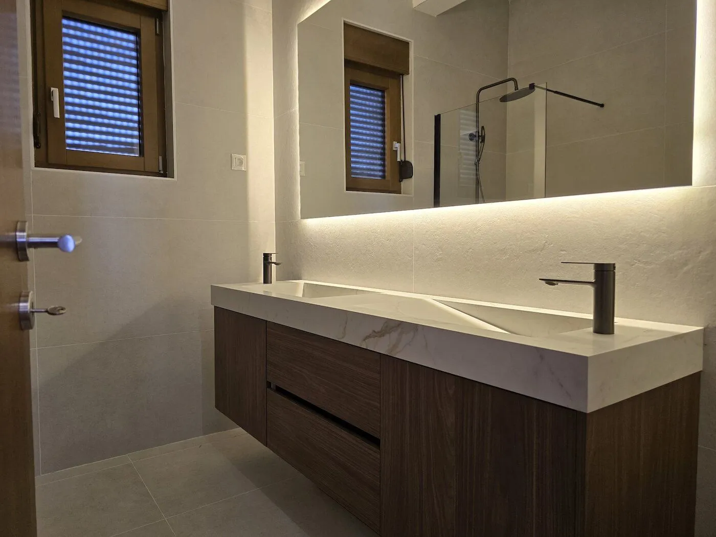 Modern bathroom with a double vanity and a large backlit mirror.