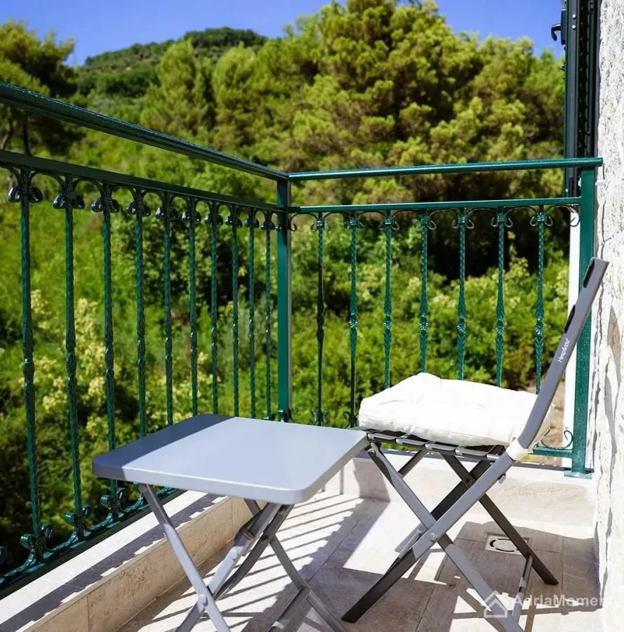 Manji balkon sa stočićem, stolicom i ogradom od kovanog gvožđa.