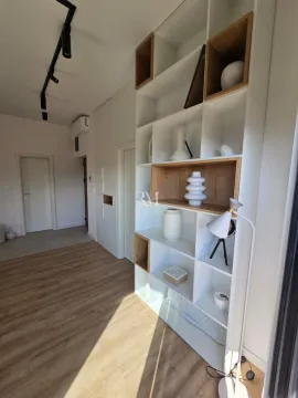 Modern living room interior with a large white shelving unit and parquet flooring. - image 4