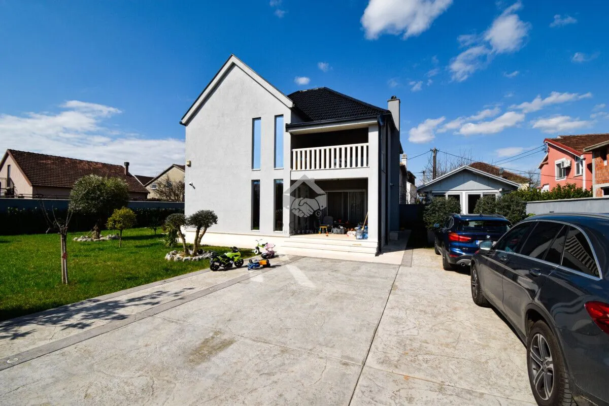 View of the yard and the front facade of a family house with parking space.