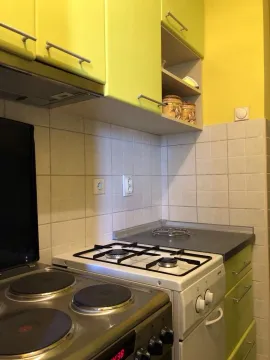 Small kitchen with a stove and yellow kitchen cabinets. - image 10