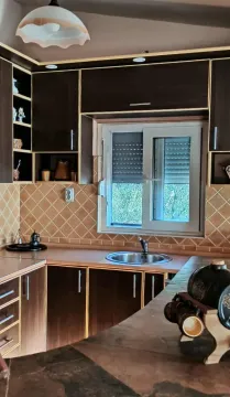 Small kitchen with dark wooden cabinets and a sink beneath the window. - image 5