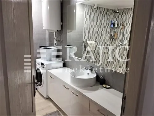 Modernly equipped bathroom with a washbasin, washing machine, and shower.
