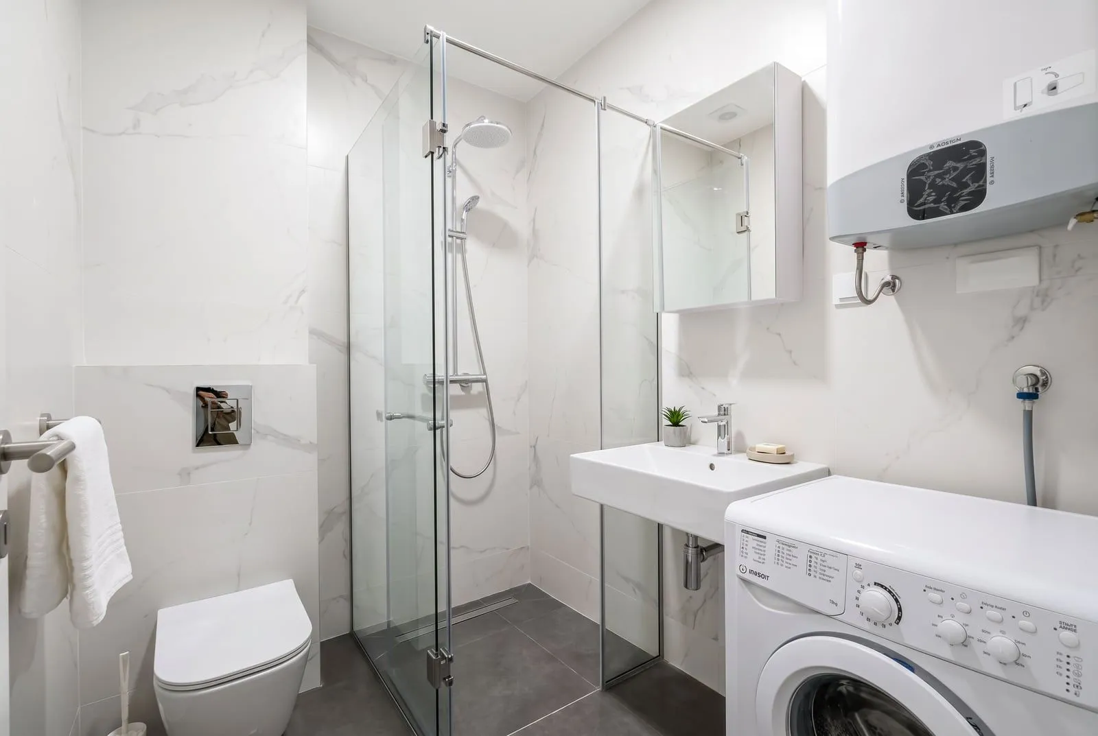 Modern bathroom with a walk-in shower, washbasin, and washing machine.
