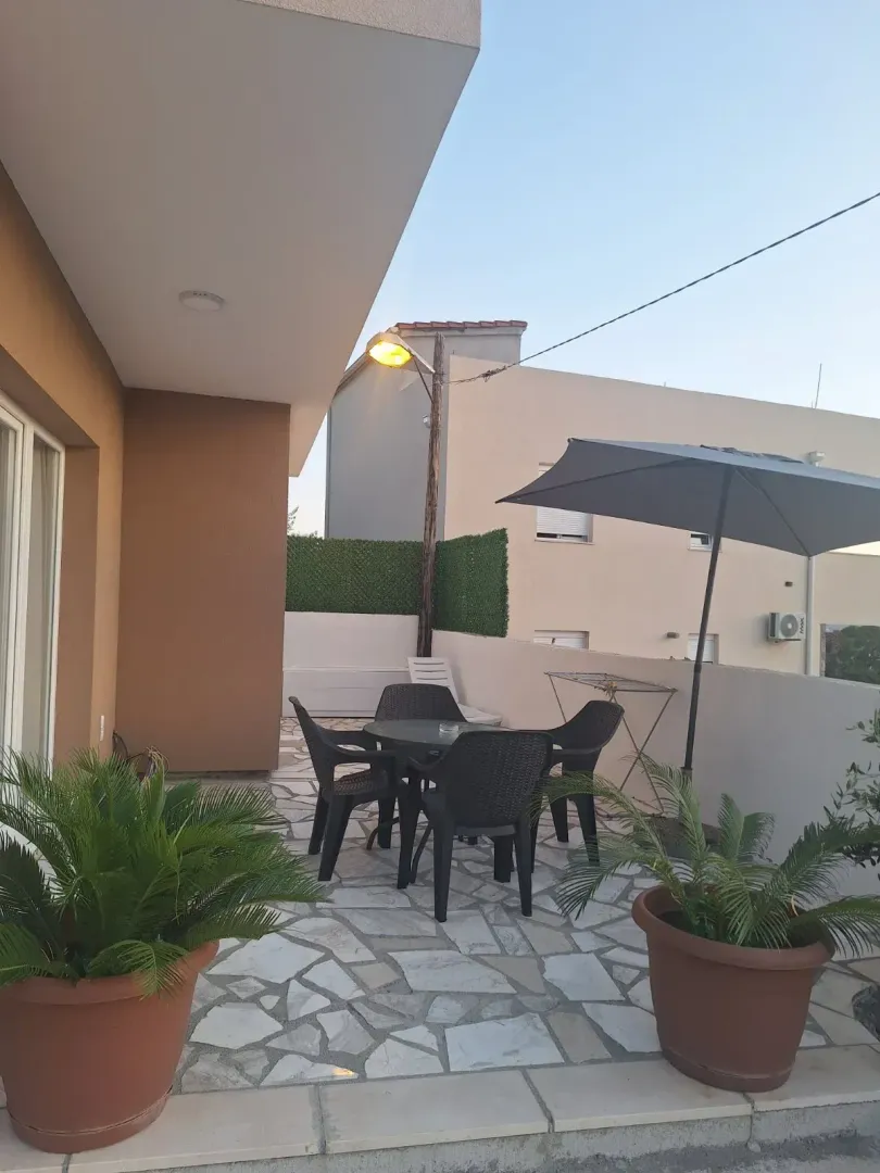 Covered terrace with outdoor seating and a sun umbrella.
