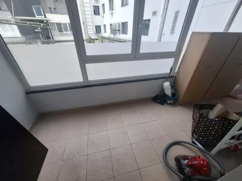 Zastakljeni balkon sa keramičkim pločicama na podu i pogledom na susedne zgrade. - image 18