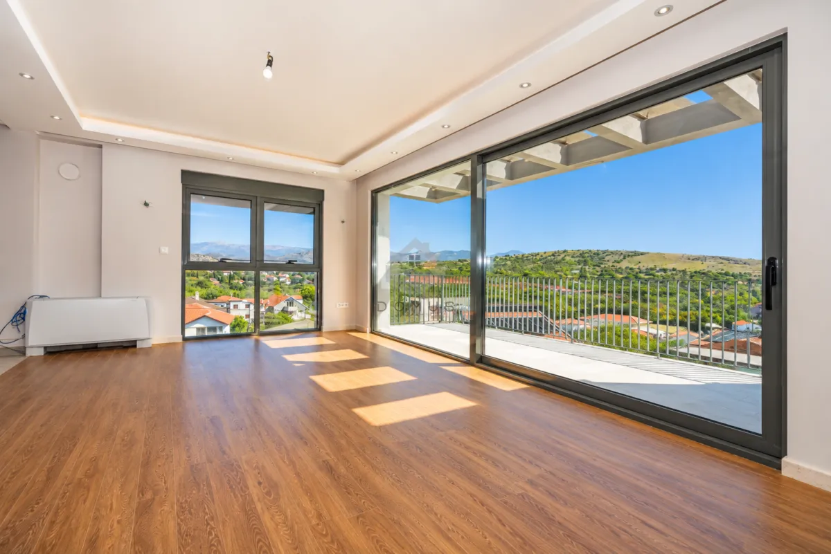 Empty living room with large glass surfaces and access to the terrace.