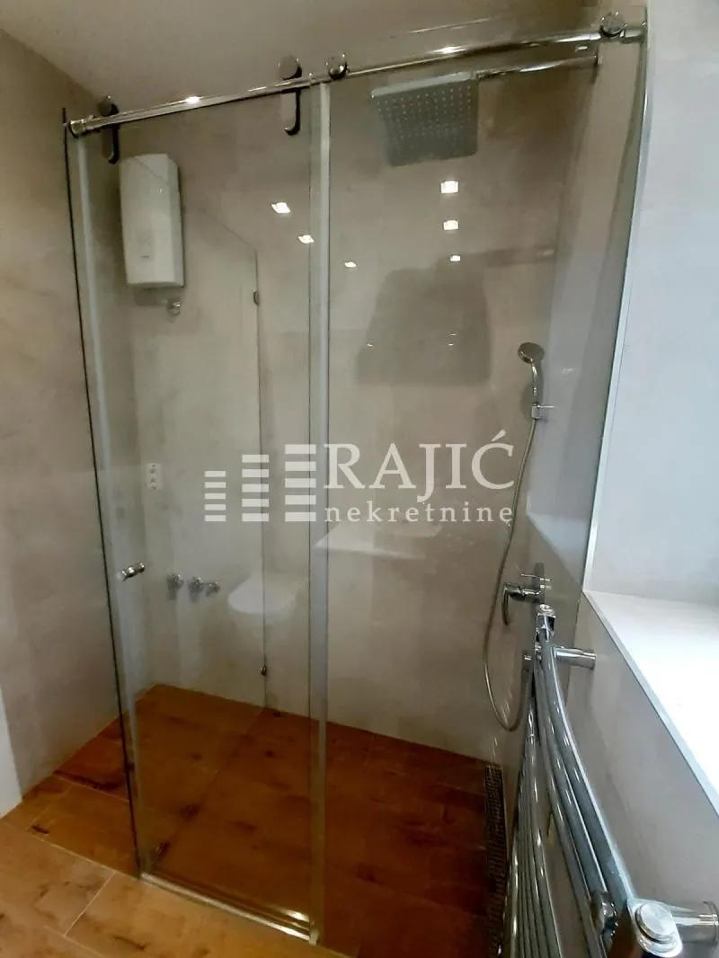 Modern bathroom with a walk-in shower and glass partition.