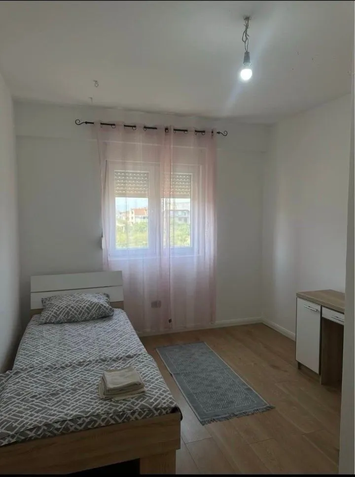 Manja spavaća soba sa krevetom, radnim stolom i prozorom.