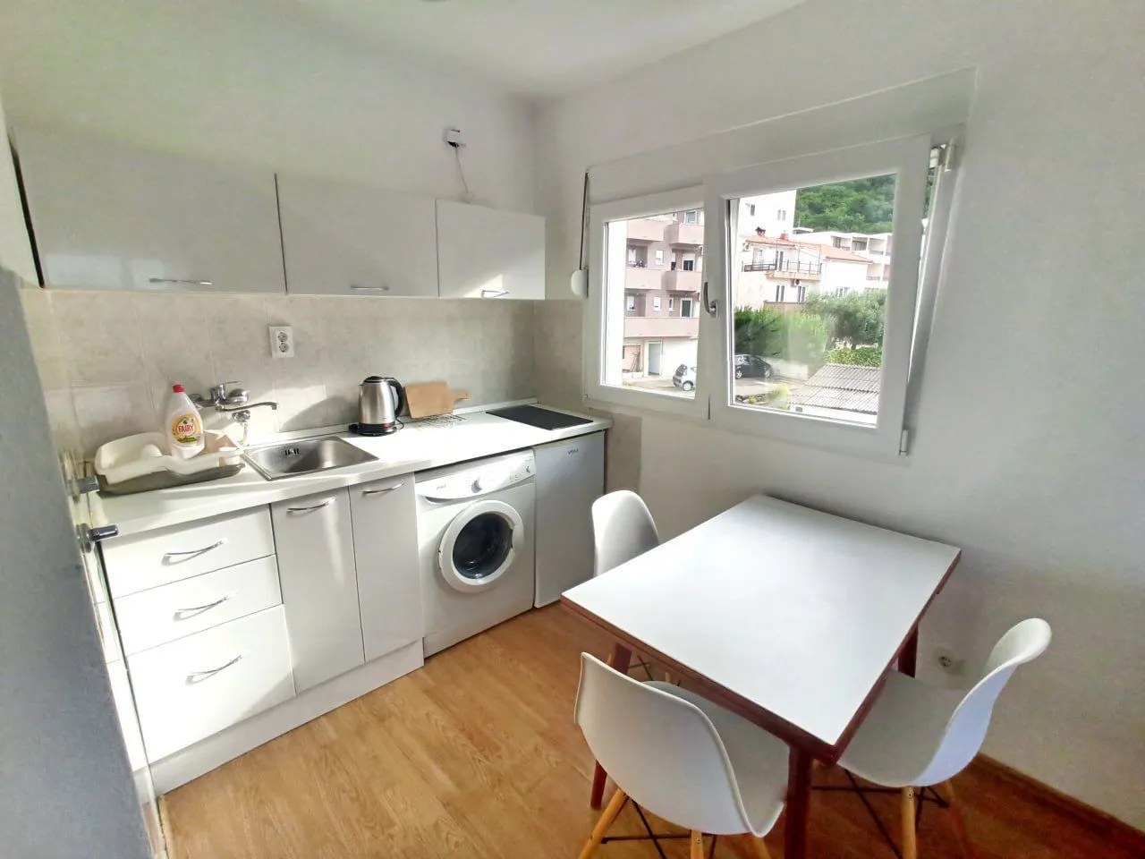 Small white kitchen with a dining table and a window.