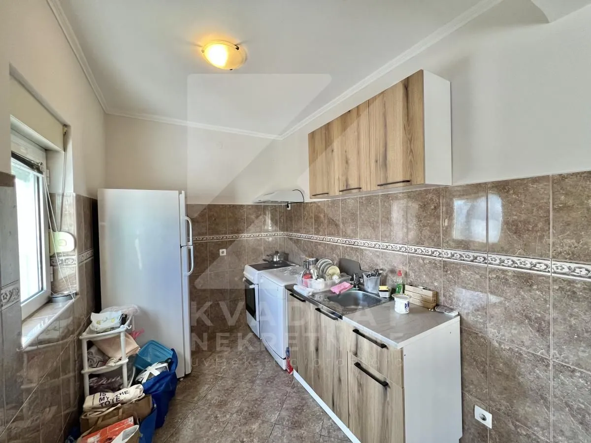 Smaller kitchen with wooden units, sink, and refrigerator.