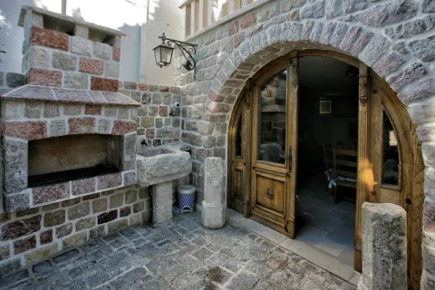 A stone courtyard featuring a built-in barbecue grill, a stone sink, and a large arched wooden door. - image 19