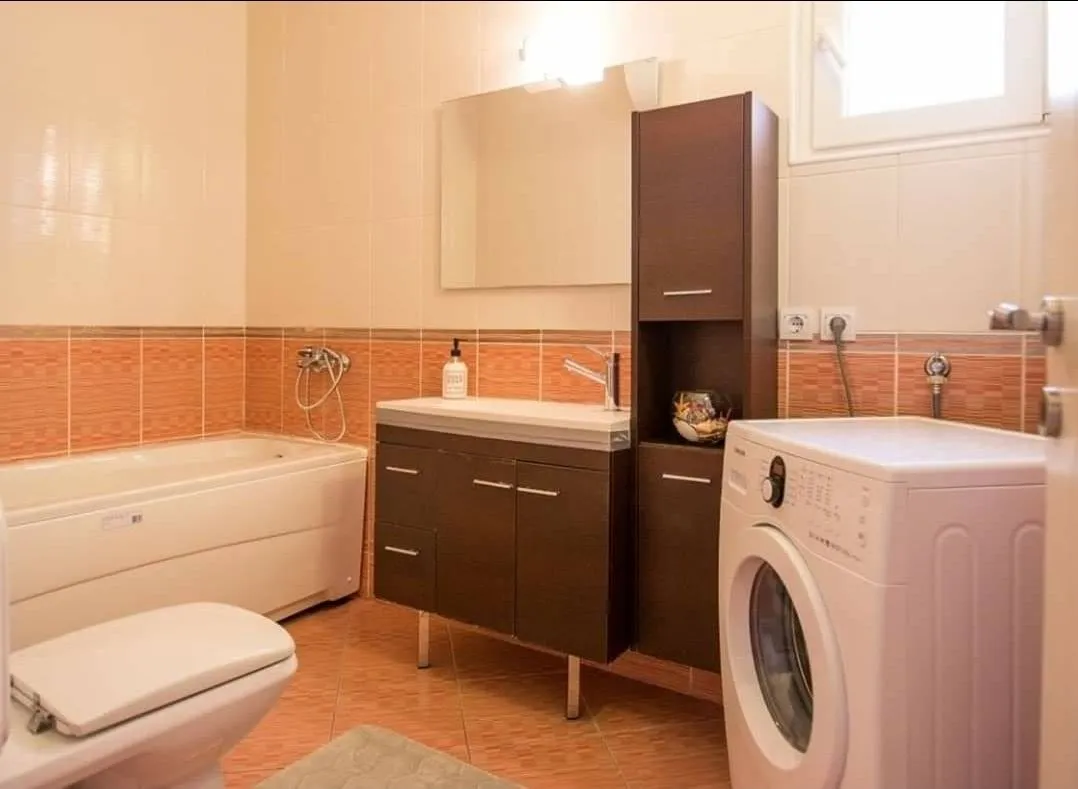 Bathroom equipped with a bathtub, vanity with sink, toilet, and washing machine.