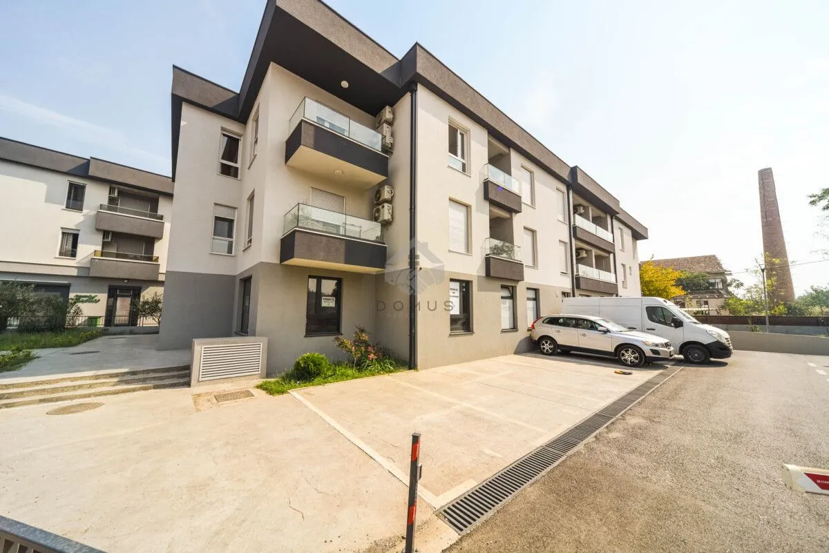 Exterior view of a modern residential building with parking in front.