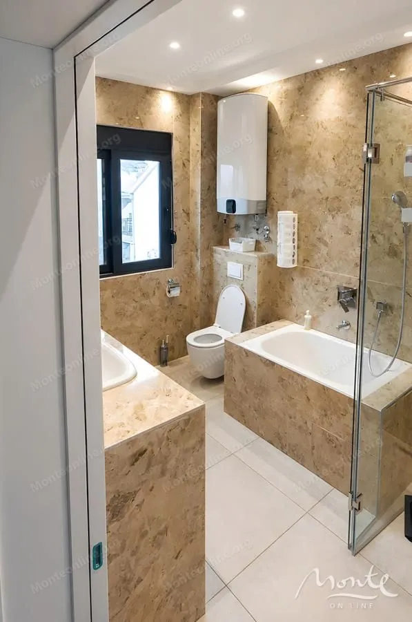 Tiled bathroom with a bathtub, glass shower enclosure, and vanity.