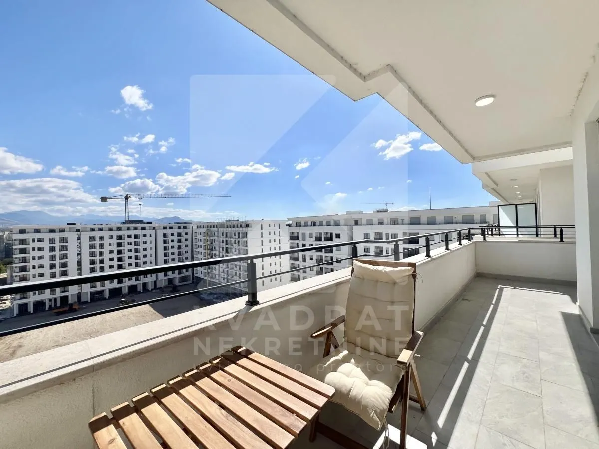 Spacious covered terrace with a table, chair, and a view of the neighborhood.