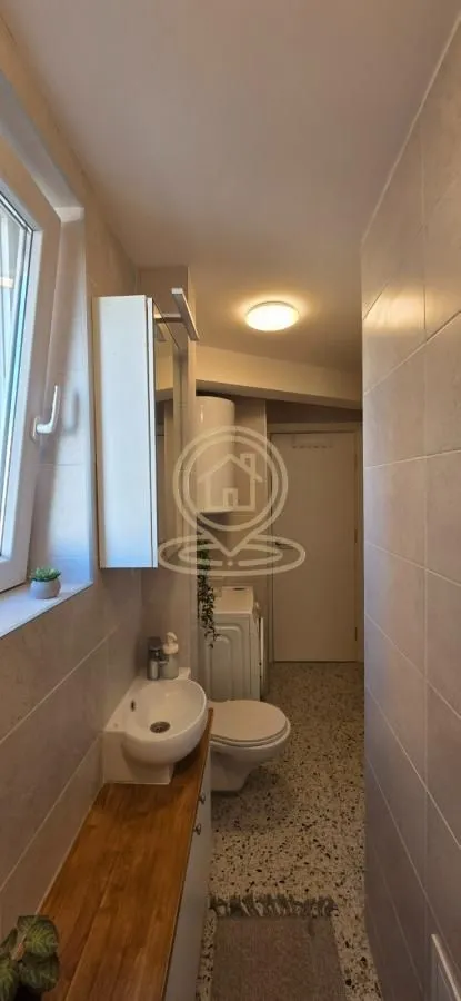 Manje kupatilo sa umivaonikom, toaletom i veš mašinom.