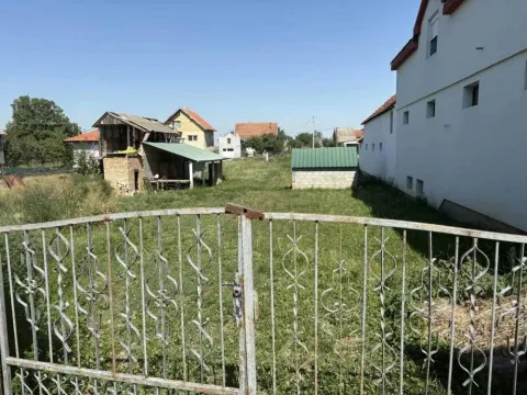 Pogled kroz metalnu kapiju na dvorište i okolne objekte. - image 9