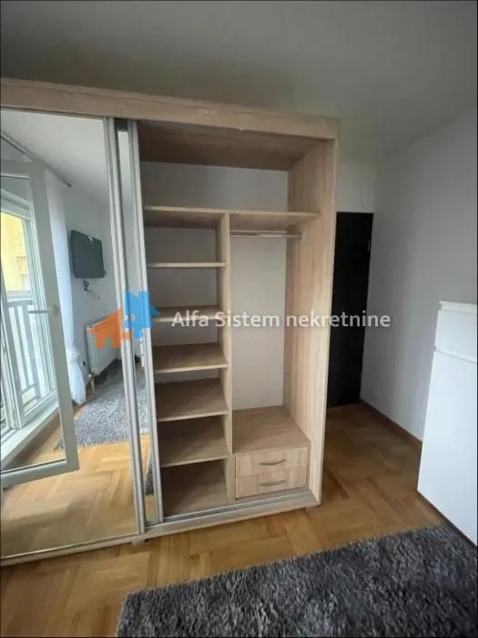 Large wooden wardrobe with shelves and sliding doors in a room.