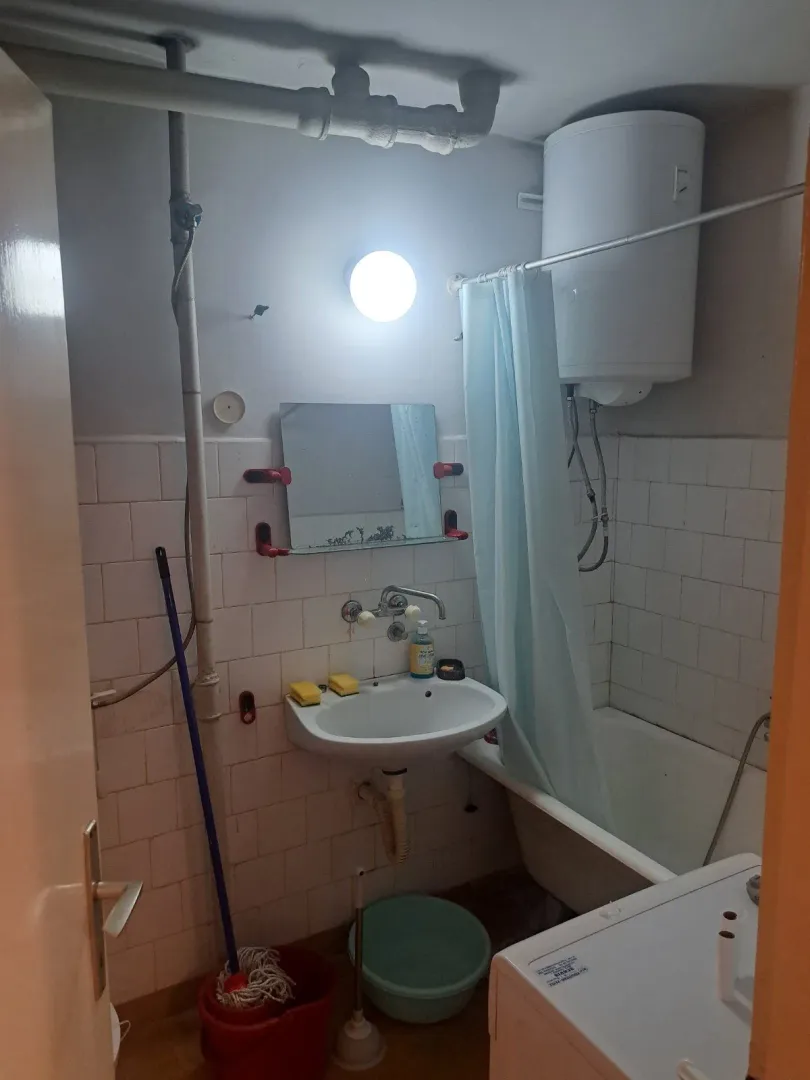 Smaller bathroom with a bathtub, washbasin, and water heater.