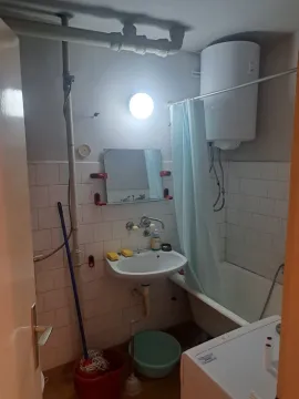 Smaller bathroom with a bathtub, washbasin, and water heater. - image 7
