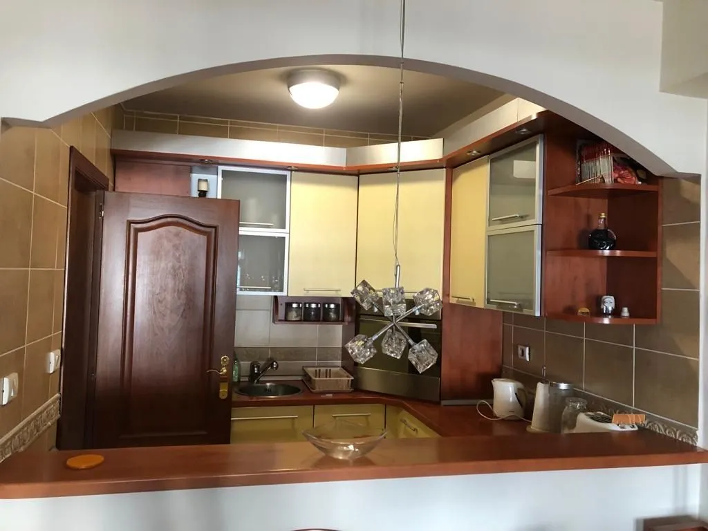 Kitchen with wooden cabinets and a bar counter seen through an archway.
