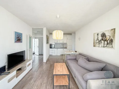 Living room with a sofa, TV, and an adjoining dining area. - image 2