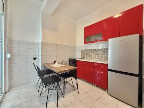 Kitchen with red cabinets, a refrigerator, and a small dining table with chairs. - image 3